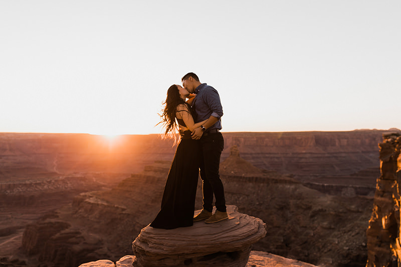 foto casal em cima da rocha com por do sol