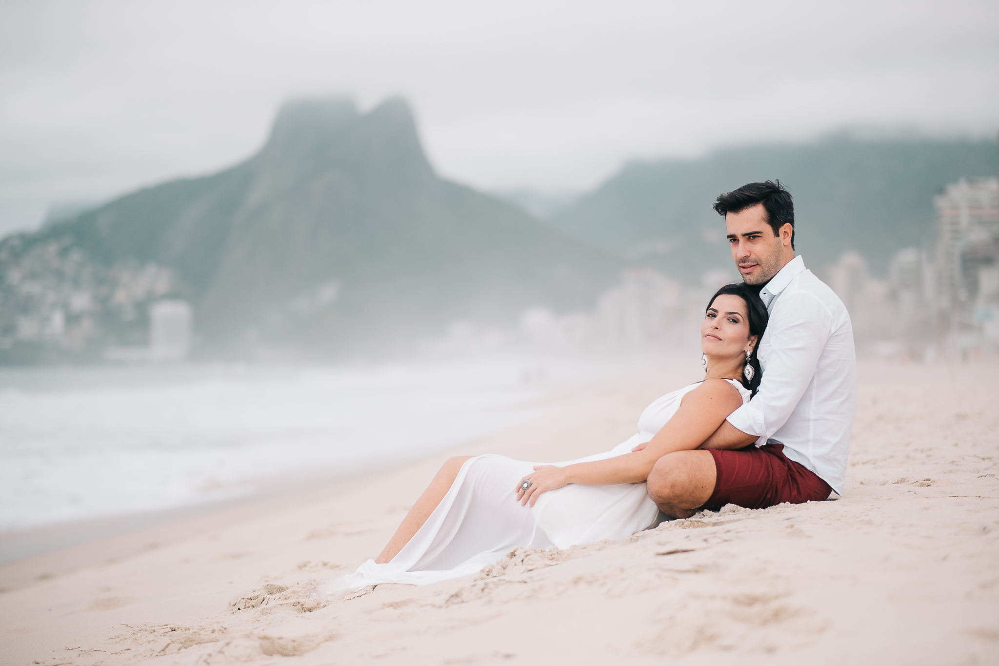 casal sentado na areia para a foto pré-wedding