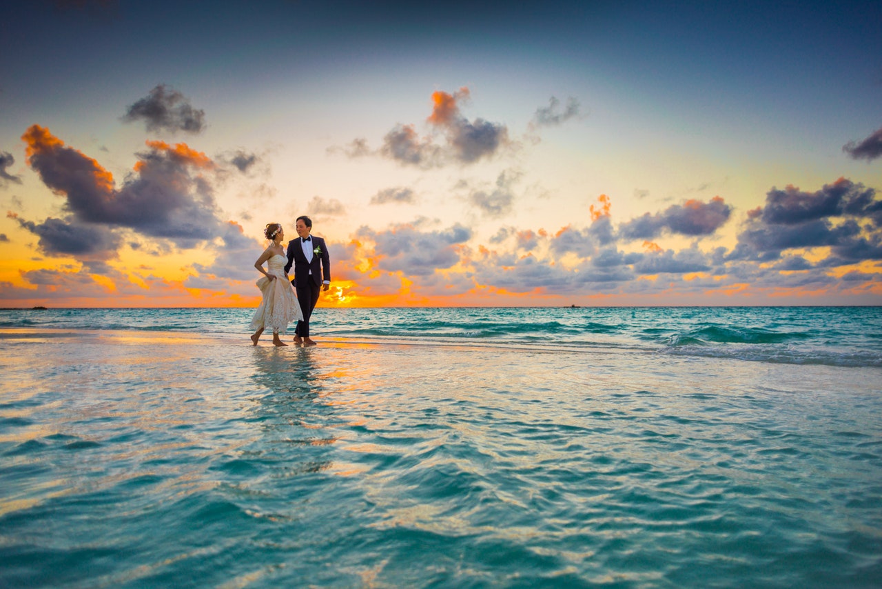 casal correndo na praia com visual do por do sol