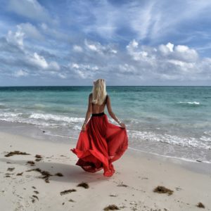 mulher na praia com vestido longo vermelho